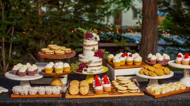 A photo of wedding desserts by Sister My Sister Bake Shop - there is a two-tier wedding cake surrounded by various desserts.