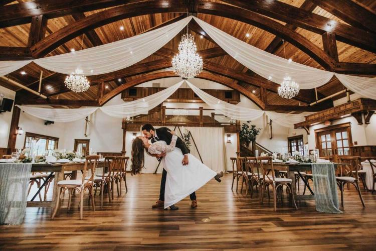 A photo of Sunnybrook Estate's Grand Room - there is a bride and groom kissing in the center of an elegantly decorated room.