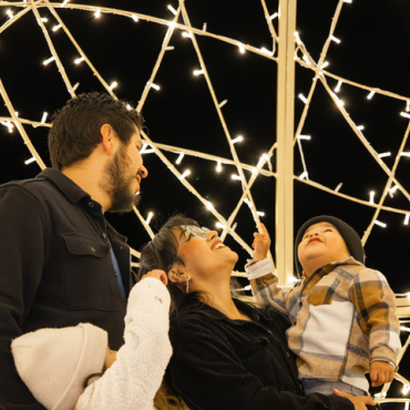 A photo of a family of four looking up towards the bright Alpine Zoo Wild Lights.