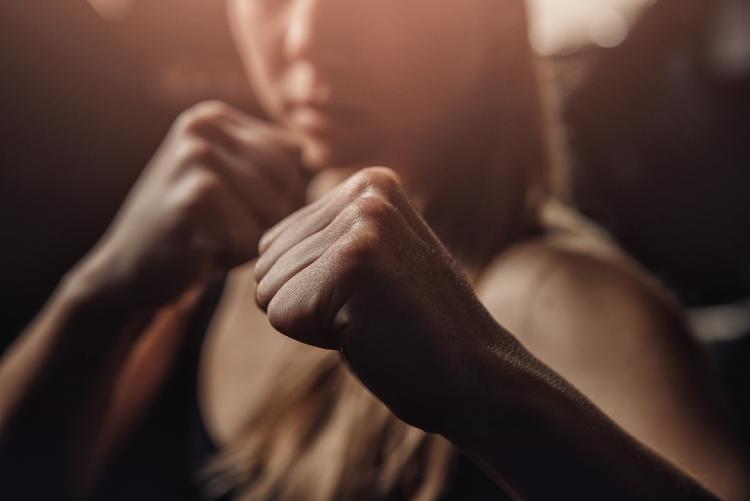 A woman raises her fists to the camera in a fighting stance. Stock photo.