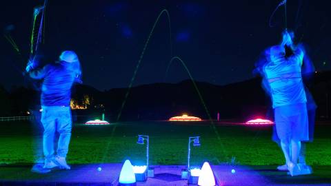 A photo of Bear Mountain Resort's Glow Golf, the brightly colored green ball flying through the air.