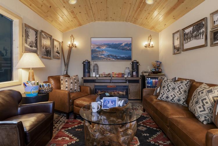 A photo of the IKON Pass Suite interior, there is an electric fireplace, couches, a minifridge, coffee table, and cozy lights