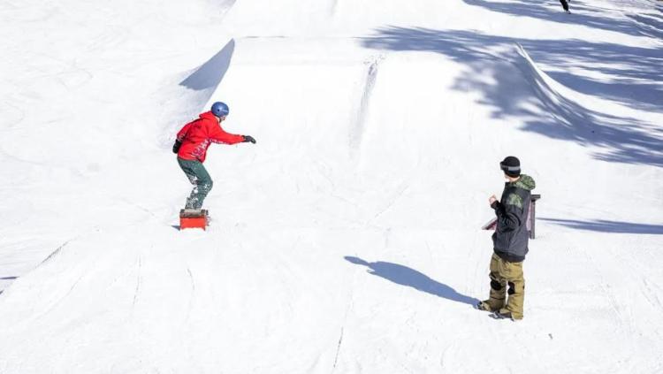 A photo from the USASA Slopestyle Competition - there is a snowboarder in front of a ramp of snow.