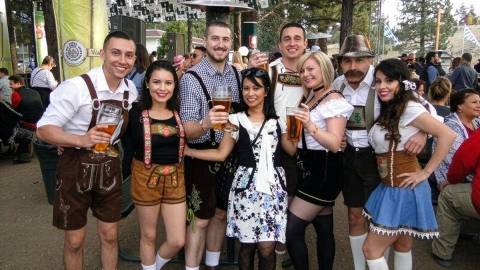 A group photo taken during the Big Bear Lake Oktoberfest - some males as well as one female are holding large beer boots.
