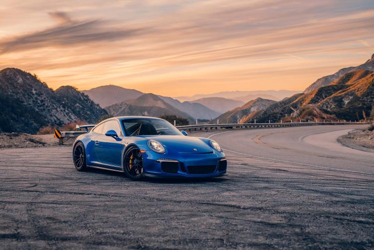 A blue porsche sits roadside along a winding mountain road. Promoting the Porsche timeline event in Big Bear Lake.