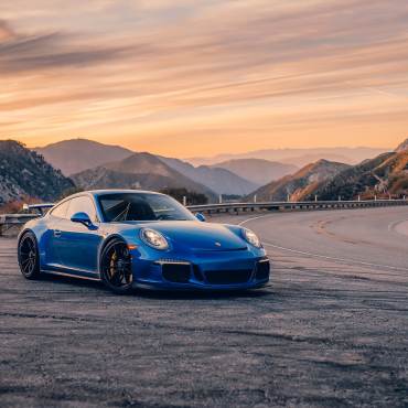 A blue porsche sits roadside along a winding mountain road. Promoting the Porsche timeline event in Big Bear Lake.