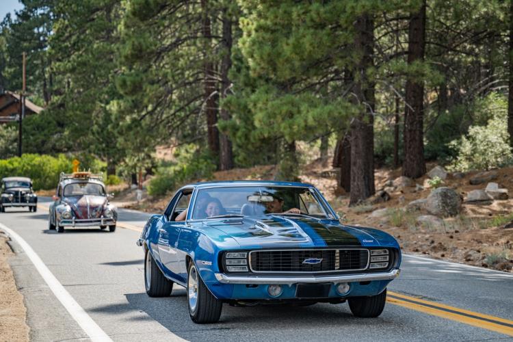 A photo taken during the Big Bear Fun Run - there is an antique Chevy Camaro leading followed by a punch buggie.