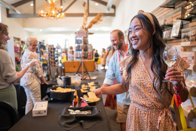 A man and lady taking part in the wine walk tasting, the lady is holding a glass of white wine while smiling.