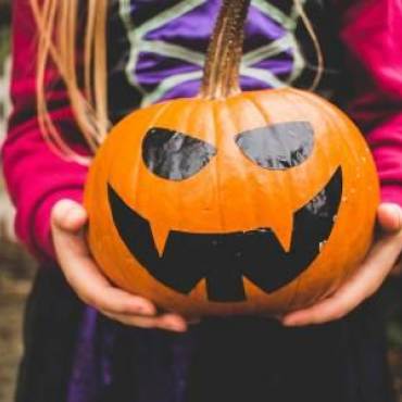 a child in a Halloween costume holds a Halloween decorated pumpkin Big Bear Lake