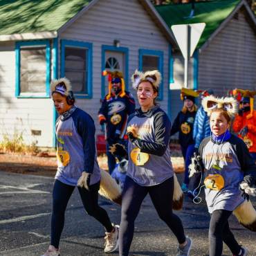 A group of three girls taking part in the Thanksgiving Turkey Trot, they are wearing face paint while dressed as Fennec foxes