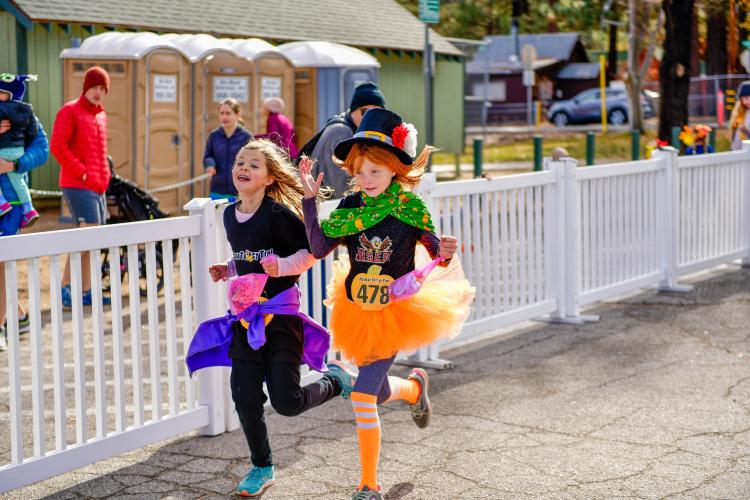 A photo of two girls running during the Thanksgiving Turkey Trot event, one is dressed as a leprechaun.