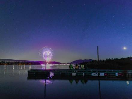 people sit on a dock on Big Bear Lake and admire the 4th of July fireworks show as fireworks reflect off of the lake