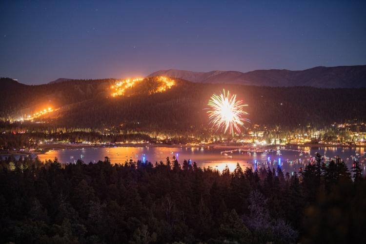 Bright fireworks displayed mid-air during Big Bear Lake's 4th of July celebration - the mountains and lake are visible.