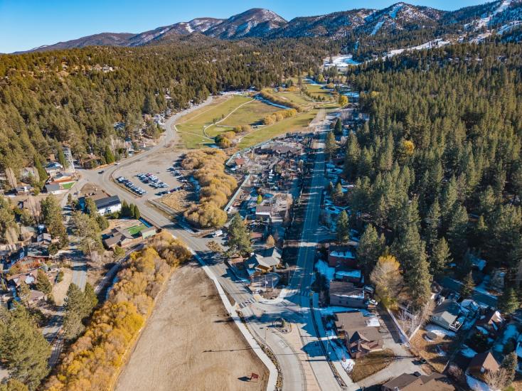 An aerial drone shot of the Moonridge Corridor, the fall colored leaves and snow topped mountains are seen in the distance.
