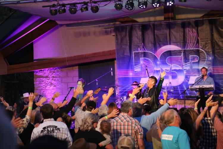 DSB Tribute to Journey plays on stage at the Music in the Mountains concert event in Big Bear Lake, CA. A large crowd dances.