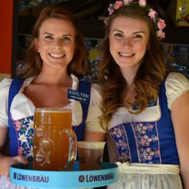 Waitresses smile at the camera and serve beer at Oktoberfest in festive outfits in Big Bear Lake, CA