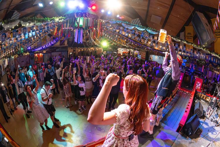 Wide angle of the Big Bear Lake Oktoberfest - two band members on stage are raising their hands for the large crowd in front.