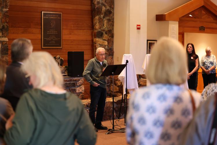 Photo taken of the awards ceremony during the Plein Air arts competition, the crowd listening the elderly man's presentation.