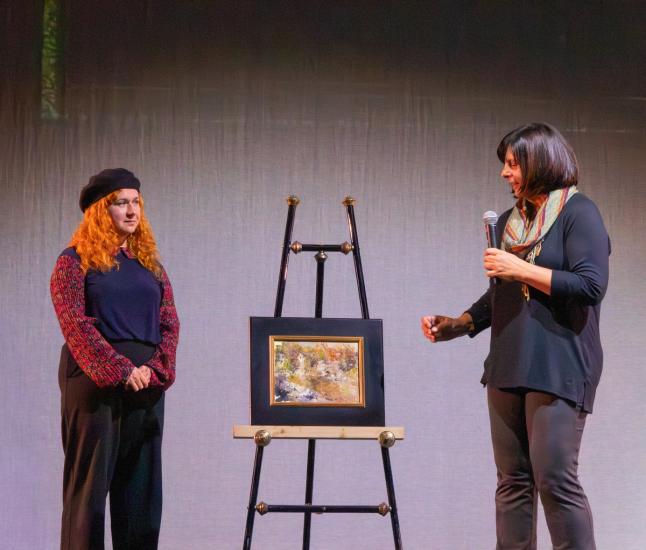 A photo of the Plein Air Awards Ceremony, Lisa Mozzini-McDill is seen talking to the second place winner of the competition.