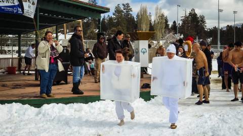 Attendees wearing ice cube costumes run through the snow for the Big Bear Polar Plunge