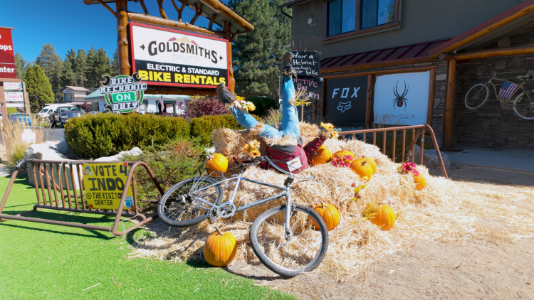 A photo of a scarecrow display at Goldsmiths Sports, there is a scarecrow in hay-bales and a bike lying on the side.