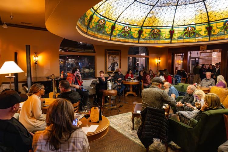 A photo of Tiffany's Bistro at Chateau Big Bear - there are musicians playing live music for a large crowd.