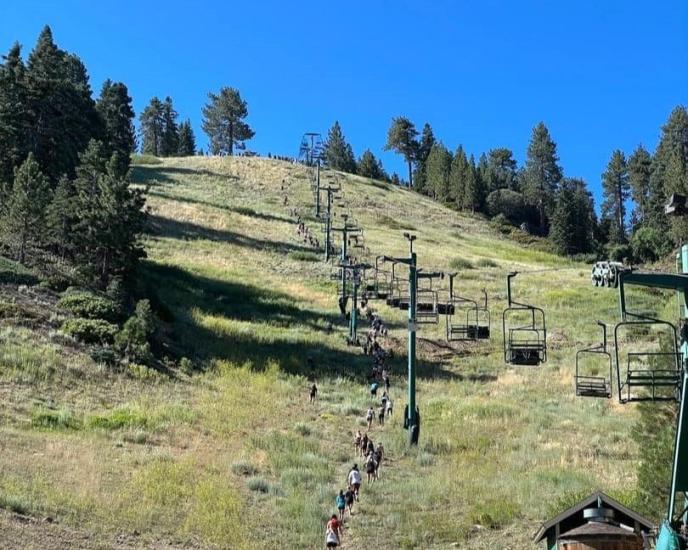 A distance photo of the Conquer The Wall competition participants hiking up the Snow Summit ski hill during summer.