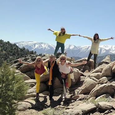 A photo of 5 females stretching during Big Bear Lake Yoga Fest, the snow topped mountains visible in the far distance.
