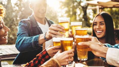 A group of six people enjoying a toast, their glasses are filled with foamy beer.