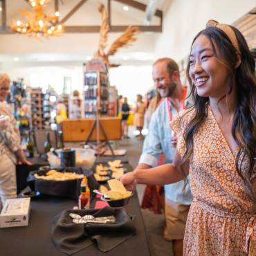 A man and lady taking part in the wine walk tasting, the lady is holding a glass of white wine while smiling.