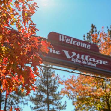 trees with orange and yellow leaves surround the Welcome sign for The Village at Big Bear. Credit Sam Rice