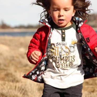 A boy in a red jacket runs through the grass near Big Bear Lake.