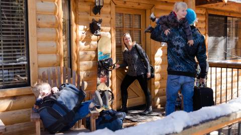family outside cabin in snow