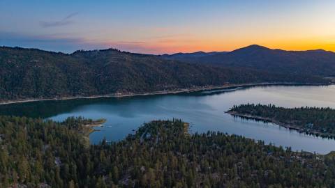 A photo of Big Bear Lake taken during a Golden Hour sunset, the lake and mountains visible in the distance.