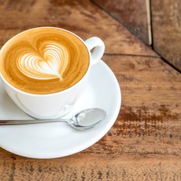 A cup of coffee topped with foamy coffee art in the shape of a heart.