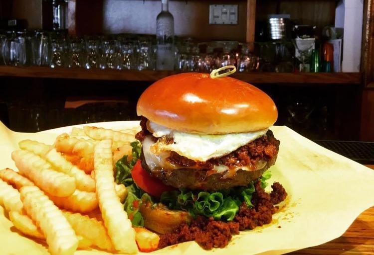 Santana and Maverick's burger with mozzarella cheese, a fried egg, and a side of fries