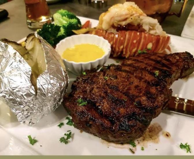 A photo of a surf and turf dish at Santana & Mavericks, on the plate there is a steak, a lobster tail, butter, and broccoli.