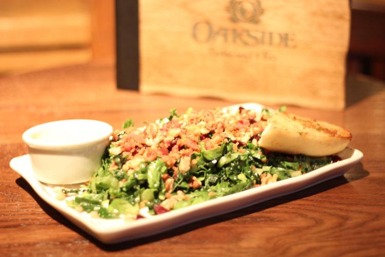 A plate with salad, a piece of bread, and a cup of dressing from Oakside restaurant in Big Bear Lake, CA.