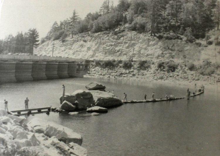 people walk on rock formations in front of the new Big Bear Lake Dam