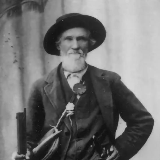An old black and white photo of William Francis "Grizzly Bill" Holcomb - he is wearing a prospecting hat and coat.