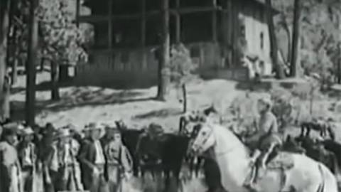 A black and white photo of a group of Big Bear settlers, one of them is on a white horse, in the background there is a house.