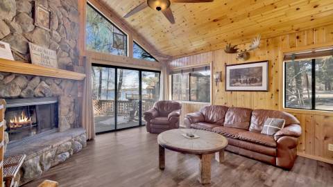 A photo of a Shore Acres Lodge cabin interior, it has a fireplace and a comfy couch - the lake is visible through the windows