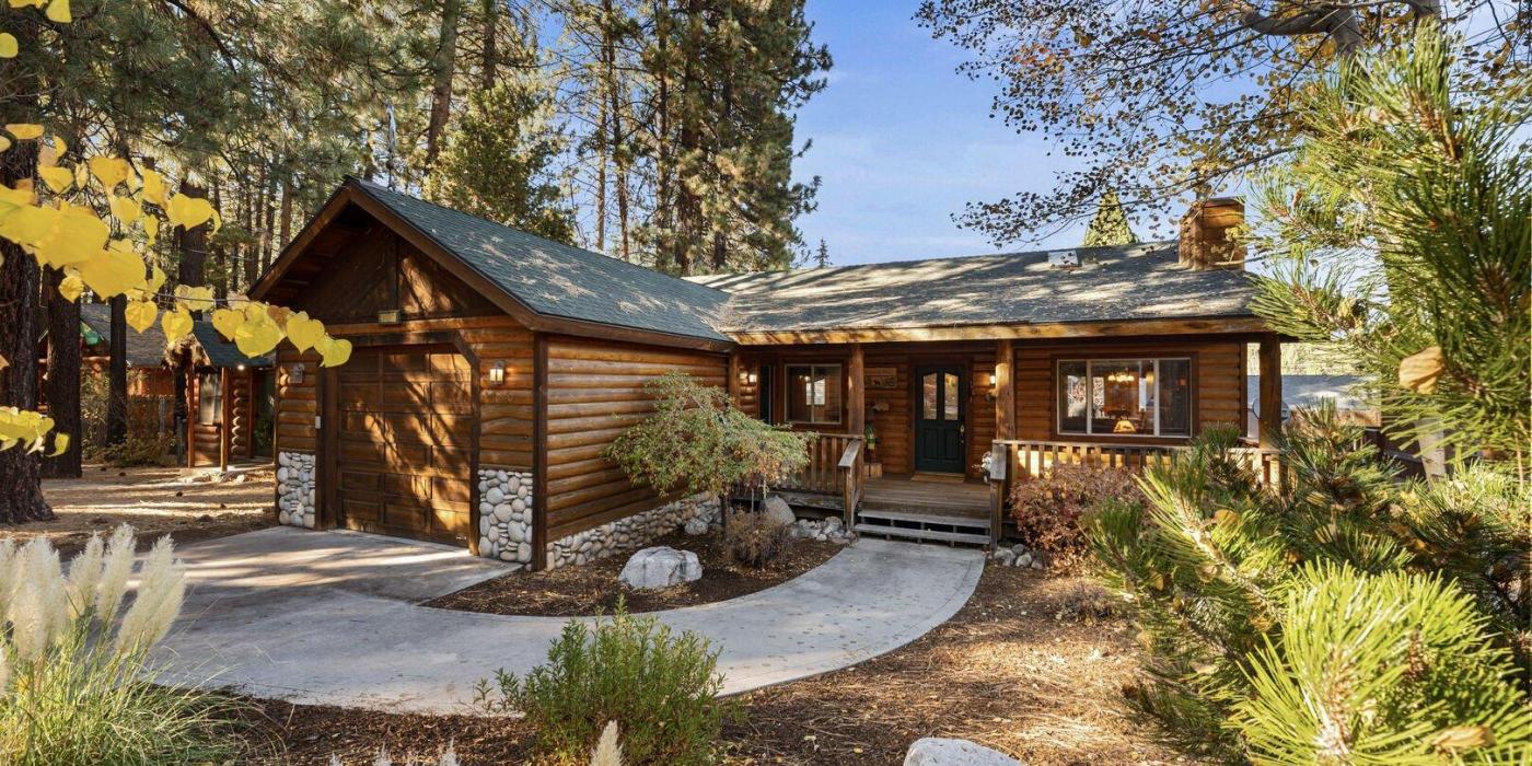 A photo of a wooden lodge cabin nestled in the forest by Big Bear Cool Cabins.