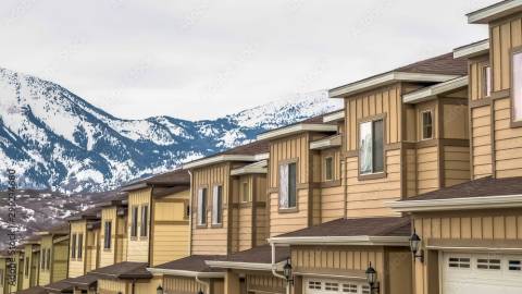 A photo of townhouses, there are snow covered mountains and a city in the distance.