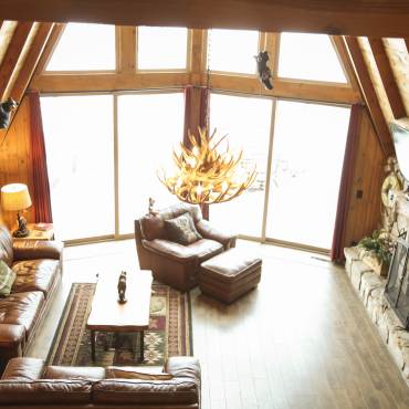 An overhead photo of a Big Bear vacation rental, there is two medium sized couches and one small, the fireplace has a TV.