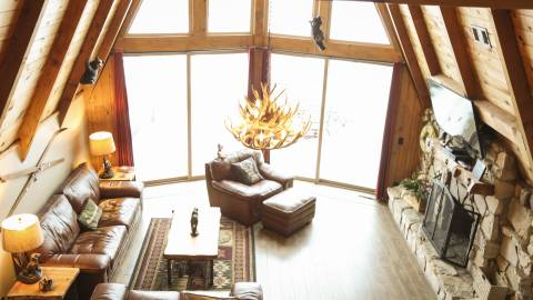 An overhead photo of a Big Bear vacation rental, there is two medium sized couches and one small, the fireplace has a TV.