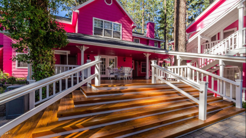 A photo of Big Bear Apples Bed and Breakfast, there are glossy wooden steps leading to a bright hot pink house.