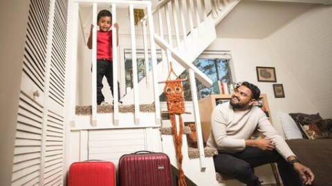 A father smiles at his son as they sit on a white staircase in their Big Bear cabin rental.
