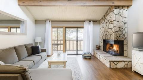 A photo of a Summit Townhouse, it has a cozy fireplace and a fully furnished living room - there is a deck visible outside.