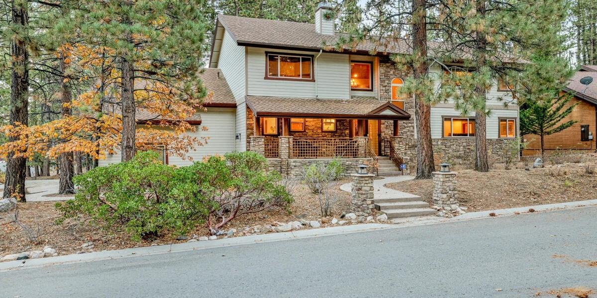 A cozy and well lit luxury vacation rental seen during fall - there are some trees with yellow leaves visible around it.